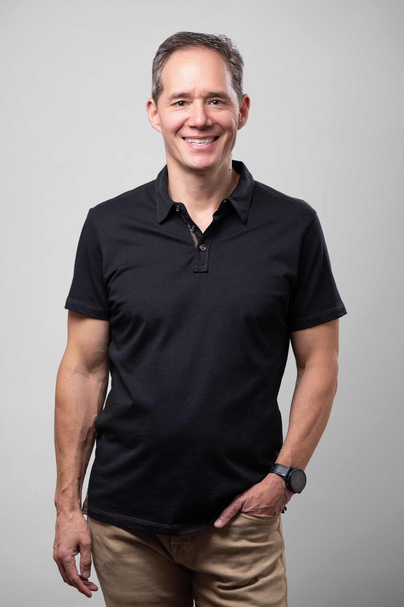 Edward Chu wearing a black polo shirt with one had in his pocket
