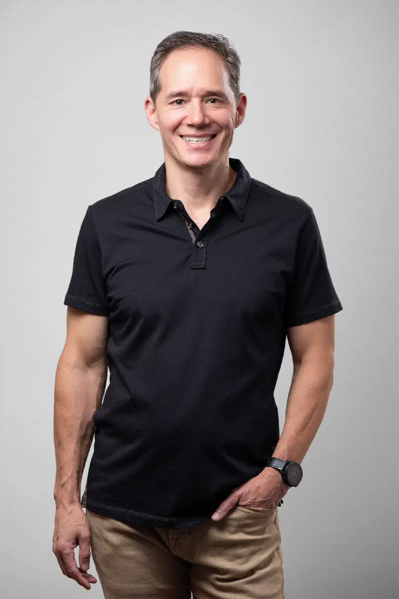 Edward Chu wearing a black polo shirt with one had in his pocket